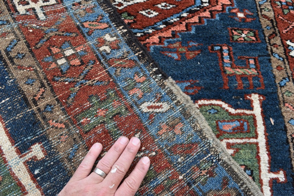 A long hand-knotted Persian Heriz runner rug featuring geometric diamond medallions on a navy blue field with terracotta red borders. View IV