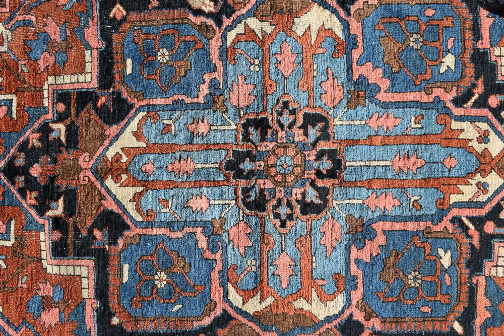 An antique hand-knotted Persian Heriz wool carpet featuring a large sky blue geometric medallion on a terracotta ground surrounded by a dark navy ornate border. View VII