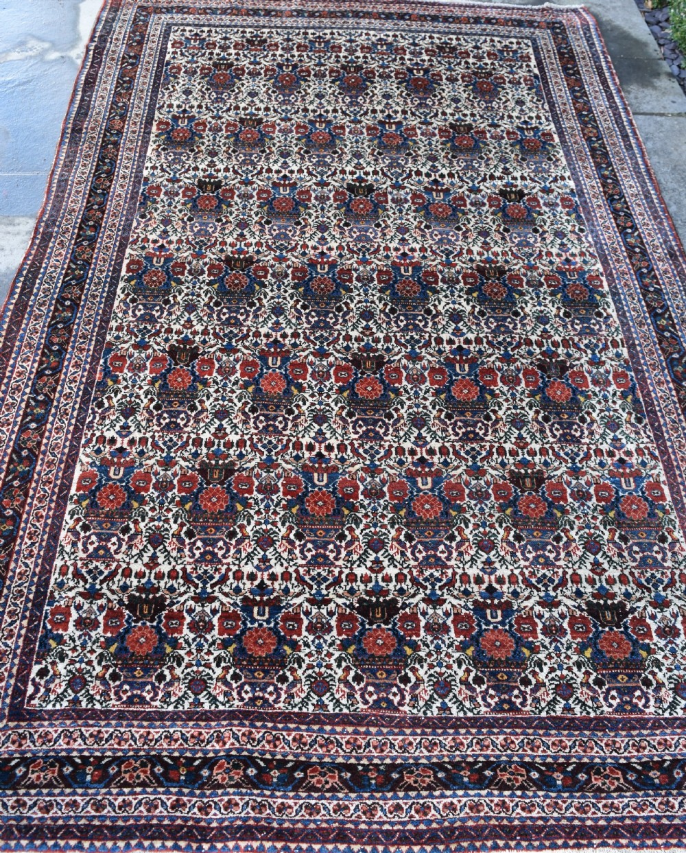An antique Persian Abadeh hand-knotted wool carpet displaying an intricate repeating floral motif across an ivory field with terracotta and navy borders. View III