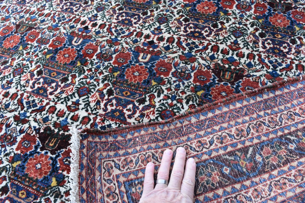 An antique Persian Abadeh hand-knotted wool carpet displaying an intricate repeating floral motif across an ivory field with terracotta and navy borders. View IV