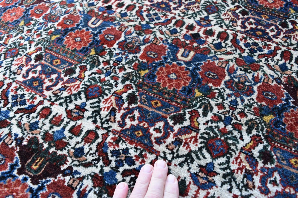 An antique Persian Abadeh hand-knotted wool carpet displaying an intricate repeating floral motif across an ivory field with terracotta and navy borders. View V