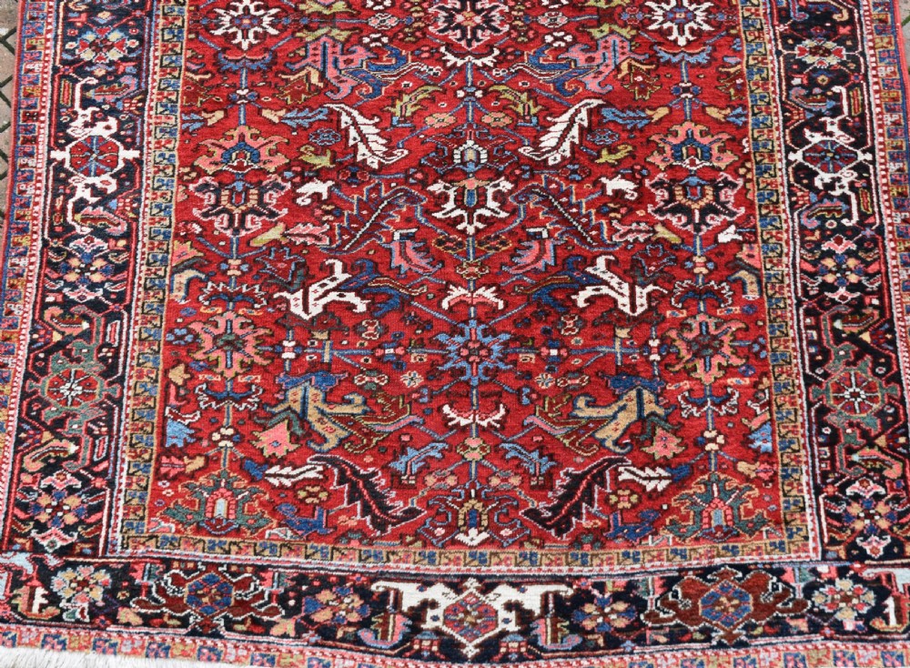 A hand-knotted Persian Heriz wool rug featuring a rich red central field with geometric patterns and a dark navy blue border. View II
