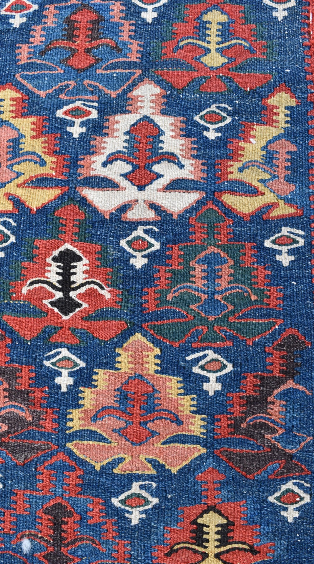 An extra long, hand-woven wool kilim runner rug featuring geometric tribal patterns in navy blue, red, cream, and ochre with fringed ends. View II