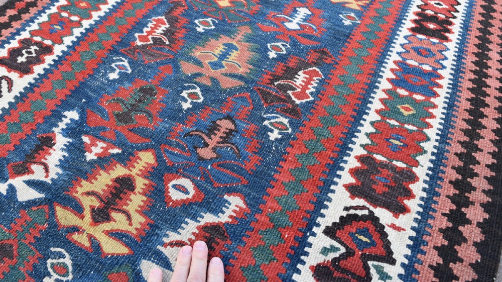 An extra long, hand-woven wool kilim runner rug featuring geometric tribal patterns in navy blue, red, cream, and ochre with fringed ends. View IV