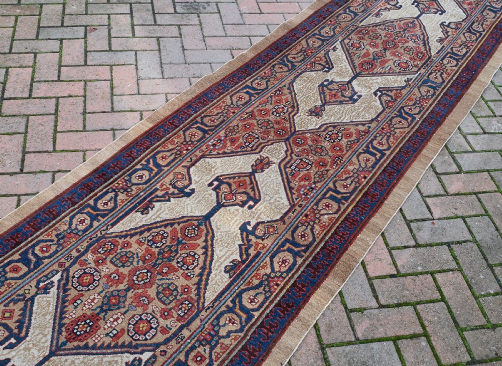 An extra long antique hand-knotted Persian Serab runner rug with geometric diamond medallions on a beige ground with terracotta and indigo accents. View III