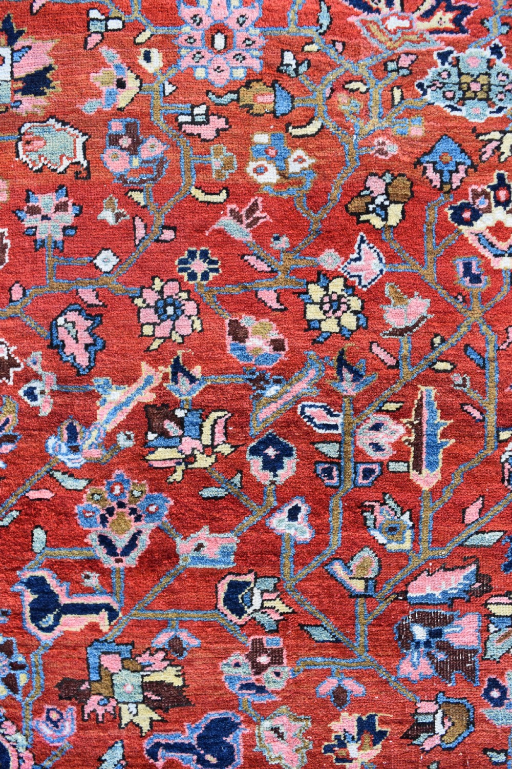 A large hand-knotted Heriz rug with a terracotta red field, central navy star medallion, and dark blue patterned border. View II