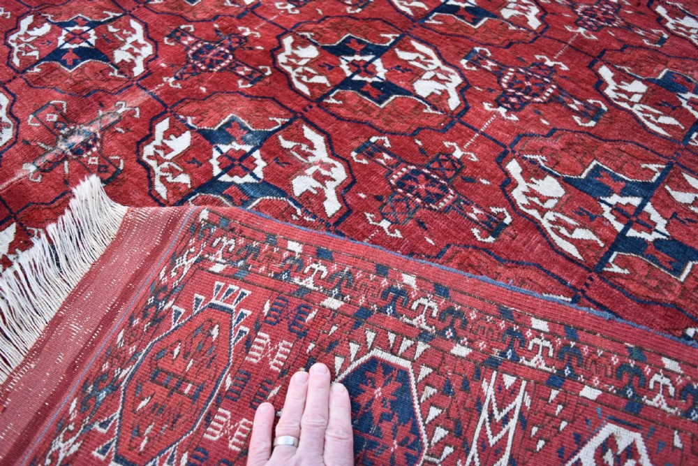 An antique hand-knotted Tekke Turkmen wool carpet featuring a repeating pattern of geometric octagonal guls on a deep red field with decorative geometric borders. View V