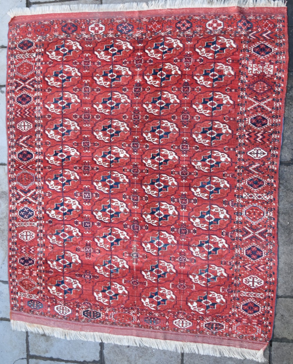 An antique hand-knotted Tekke Turkmen wool carpet featuring a repeating pattern of geometric octagonal guls on a deep red field with decorative geometric borders. View VI