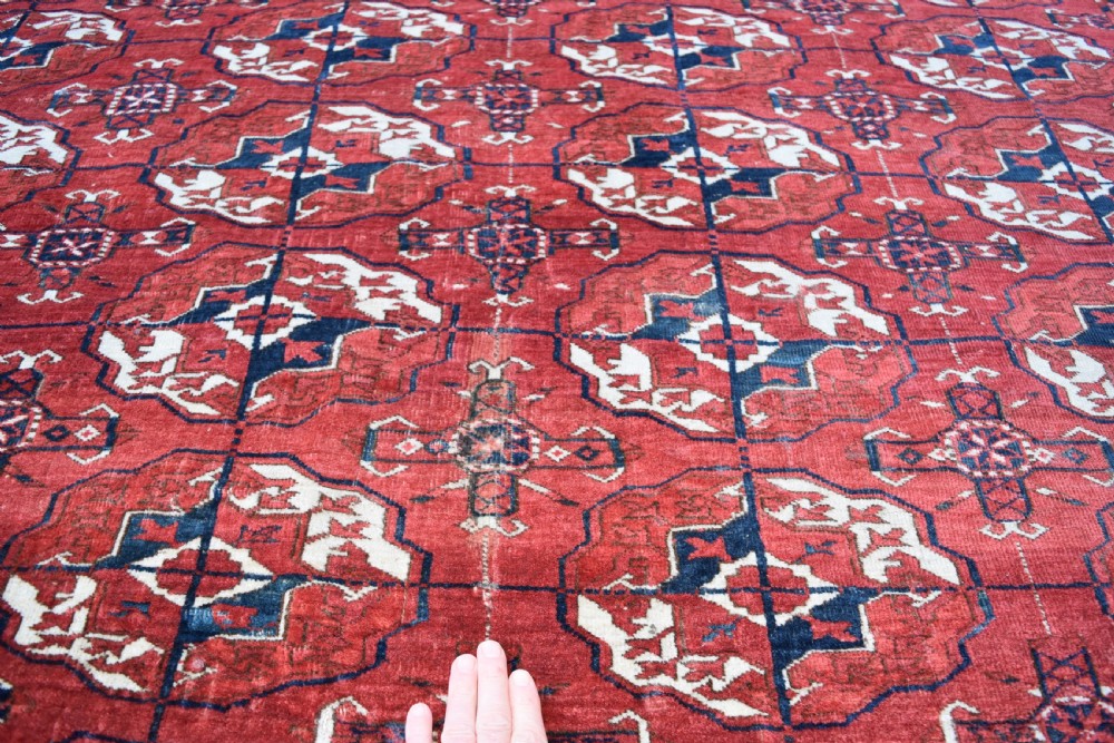 An antique hand-knotted Tekke Turkmen wool carpet featuring a repeating pattern of geometric octagonal guls on a deep red field with decorative geometric borders. View VII