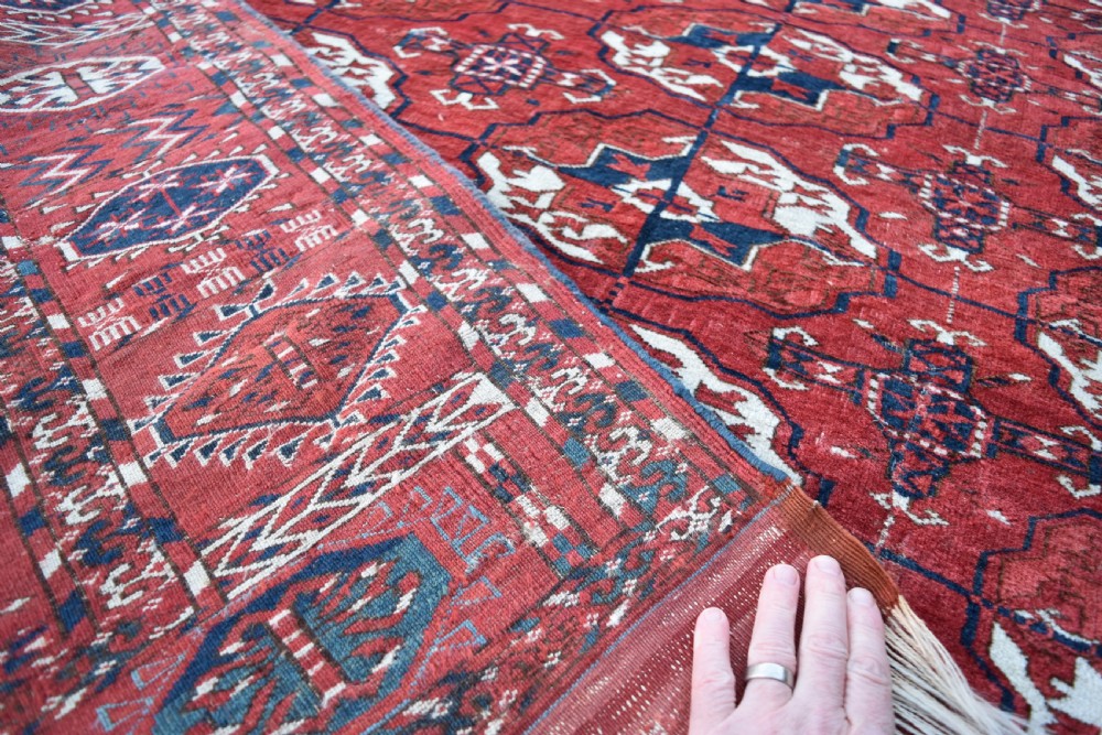 An antique hand-knotted Tekke Turkmen wool carpet featuring a repeating pattern of geometric octagonal guls on a deep red field with decorative geometric borders. View VIII