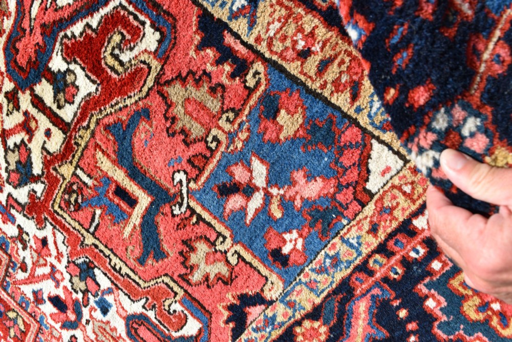 A room-sized hand-knotted Heriz carpet featuring a prominent geometric central medallion in terracotta red, navy blue, and ivory framed by a detailed border. View VIII