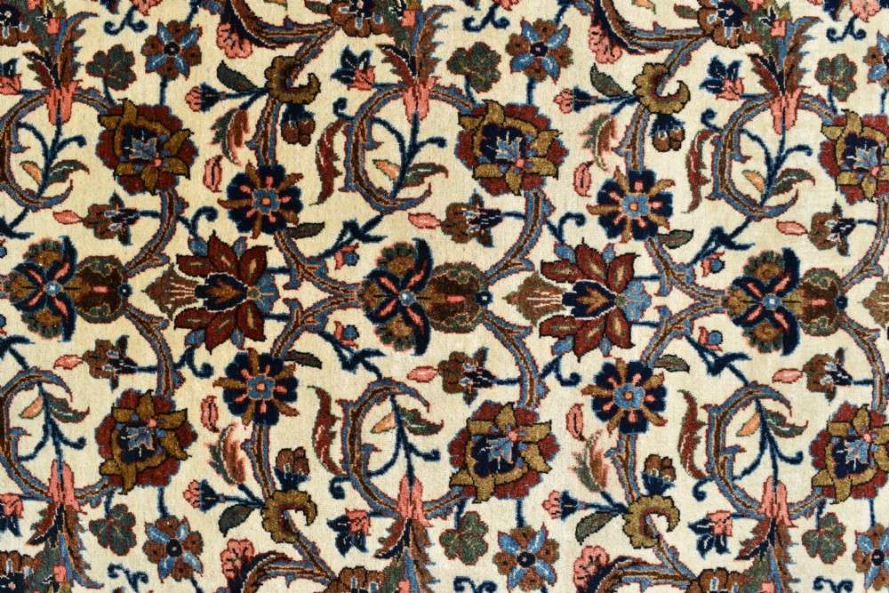 A large hand-knotted Persian Qum carpet featuring an all-over intricate floral vine motif on an ivory field, framed by multi-tiered red and blue decorative borders with fringe ends. View VI