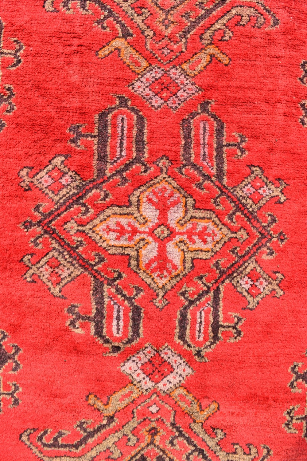 An antique hand-knotted Turkish Ushak wool carpet featuring a red field adorned with central geometric medallions and a patterned border. View VI