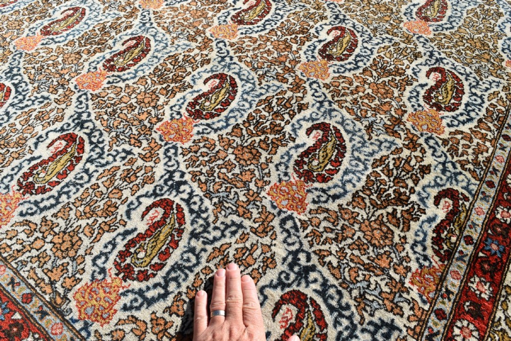 An antique hand-knotted Persian Qum carpet featuring an all-over repeating boteh paisley motif in cream, terracotta red, navy blue, and sage tones with a patterned border. View II