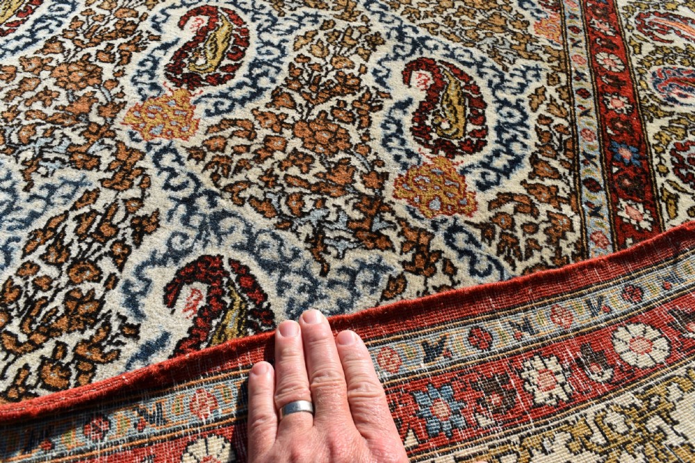 An antique hand-knotted Persian Qum carpet featuring an all-over repeating boteh paisley motif in cream, terracotta red, navy blue, and sage tones with a patterned border. View III