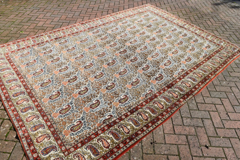 An antique hand-knotted Persian Qum carpet featuring an all-over repeating boteh paisley motif in cream, terracotta red, navy blue, and sage tones with a patterned border. View V