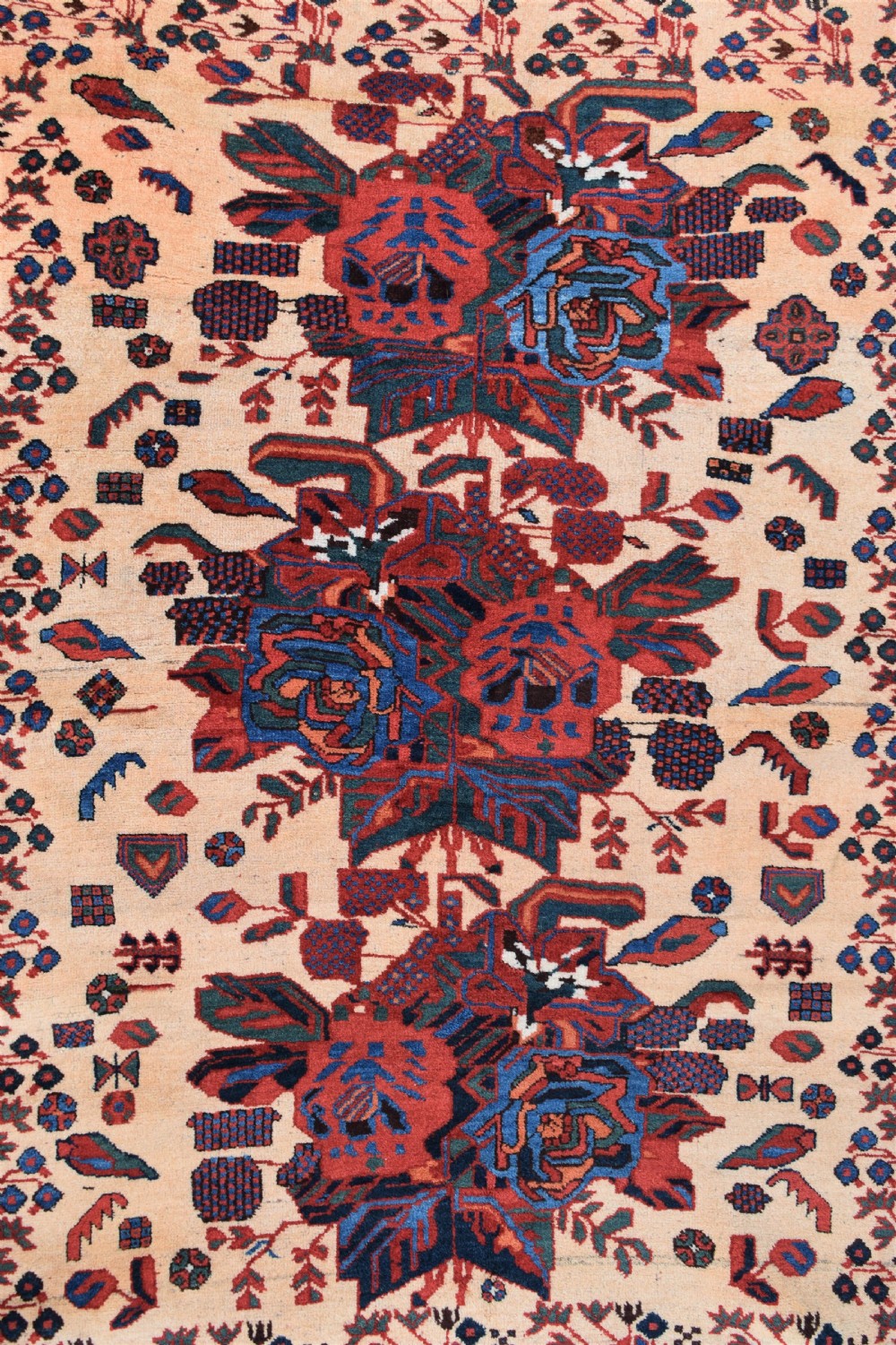 An antique hand-knotted Afshar rug featuring three central stylized floral medallions on a light peach field with intricate geometric borders in indigo and red. View II