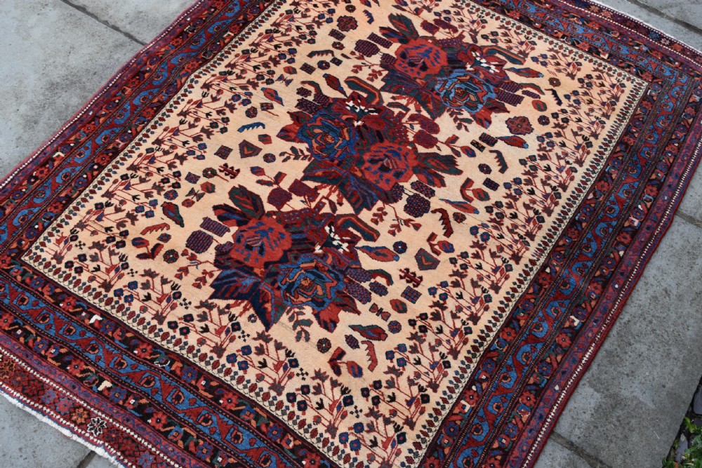 An antique hand-knotted Afshar rug featuring three central stylized floral medallions on a light peach field with intricate geometric borders in indigo and red. View III