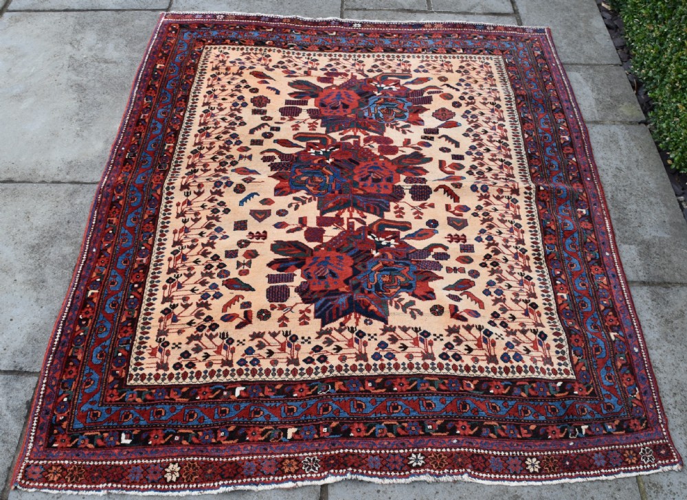 An antique hand-knotted Afshar rug featuring three central stylized floral medallions on a light peach field with intricate geometric borders in indigo and red. View V