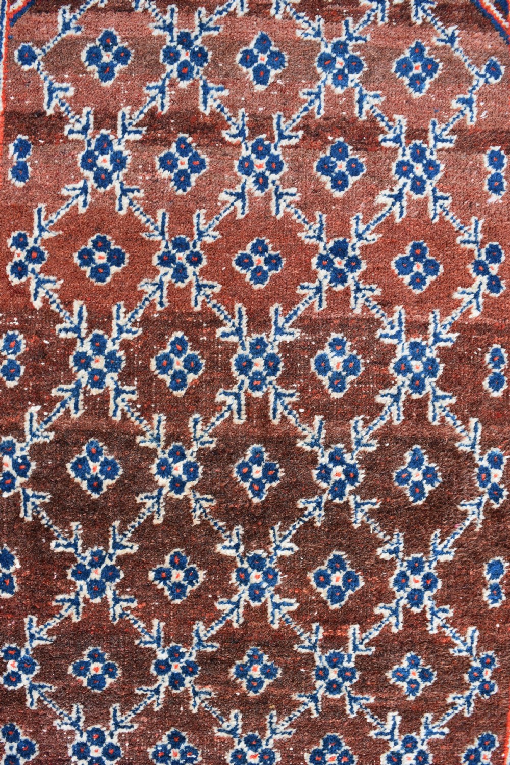 An extra long antique hand-knotted wool runner rug featuring a terracotta field patterned with repeating geometric florets and a central star emblem inside patterned borders. View II