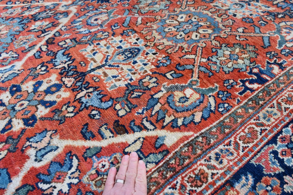 A hand-knotted Persian Mahal carpet featuring a terracotta central field with intricate floral and diamond medallions enclosed within a dark navy blue floral border. View III