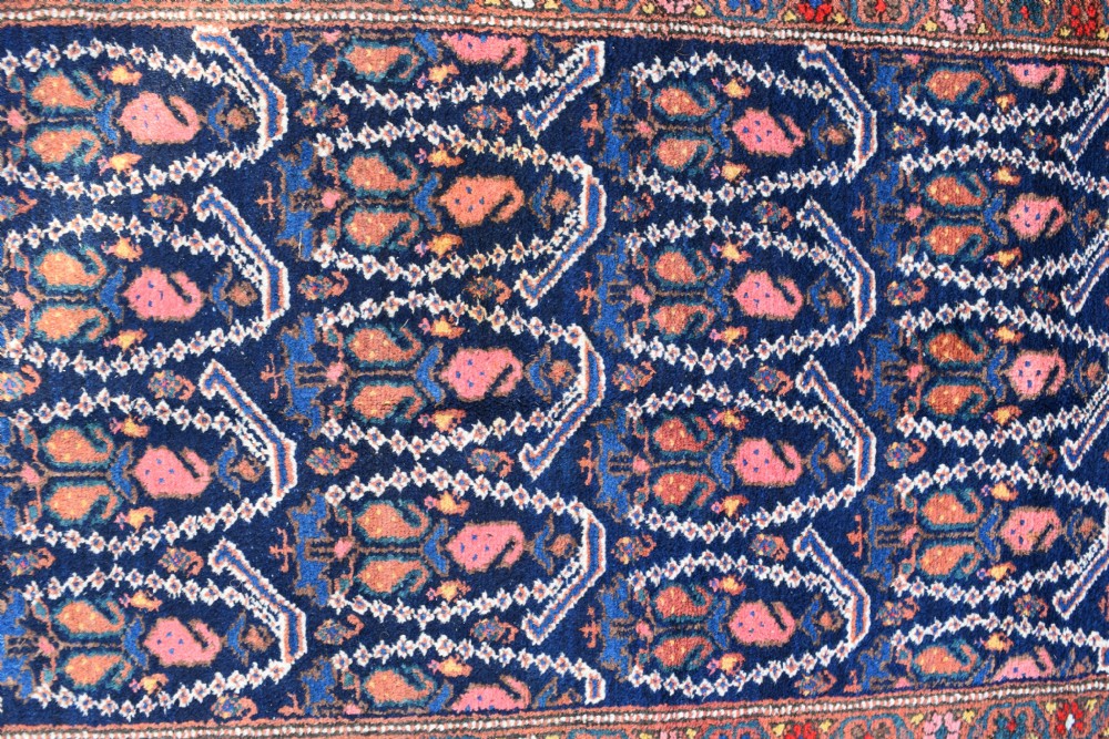 A matching pair of long antique Malayer hand-knotted wool runner rugs displaying repeating geometric boteh motifs in navy blue, terracotta red, and ivory. View III