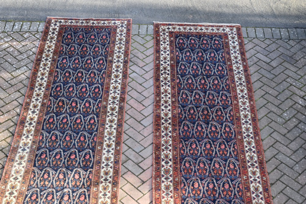 A matching pair of long antique Malayer hand-knotted wool runner rugs displaying repeating geometric boteh motifs in navy blue, terracotta red, and ivory. View VII