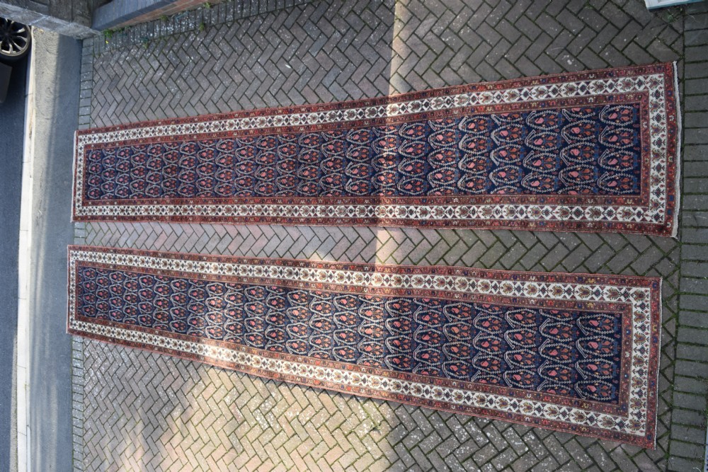 A matching pair of long antique Malayer hand-knotted wool runner rugs displaying repeating geometric boteh motifs in navy blue, terracotta red, and ivory. View VIII