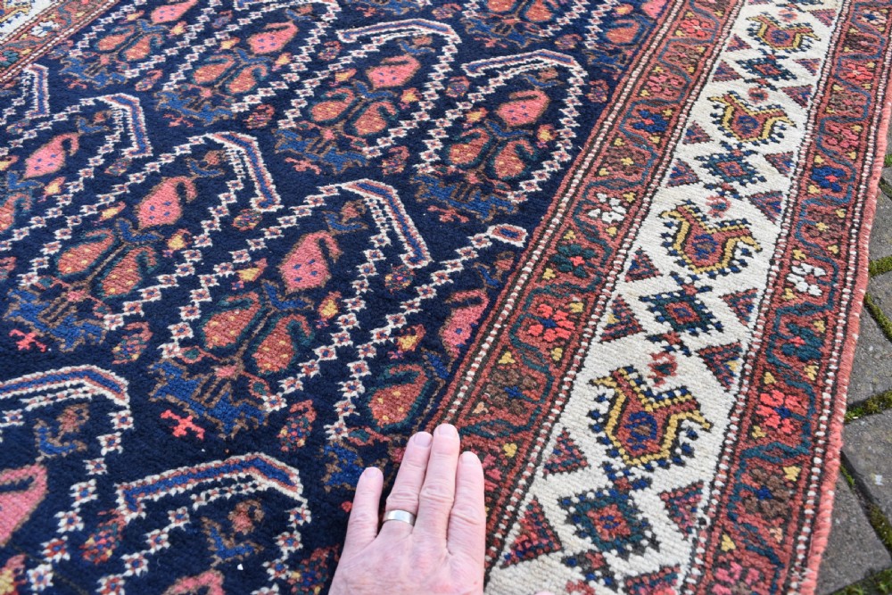 A matching pair of long antique Malayer hand-knotted wool runner rugs displaying repeating geometric boteh motifs in navy blue, terracotta red, and ivory. View IX