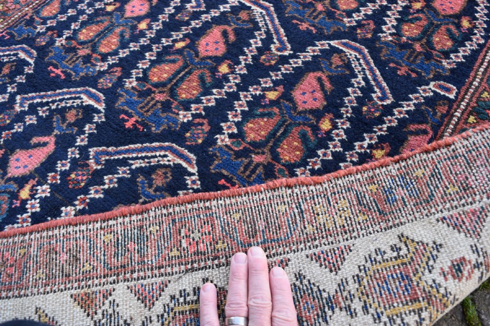 A matching pair of long antique Malayer hand-knotted wool runner rugs displaying repeating geometric boteh motifs in navy blue, terracotta red, and ivory. View X