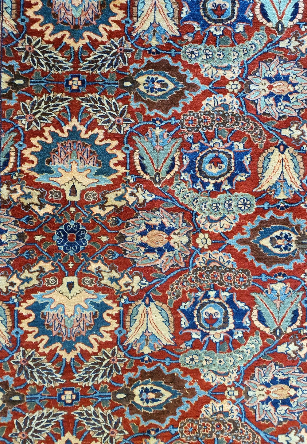 A large hand-knotted antique Tabriz carpet with an intricate floral motif across a red central field and a dark navy border. View II