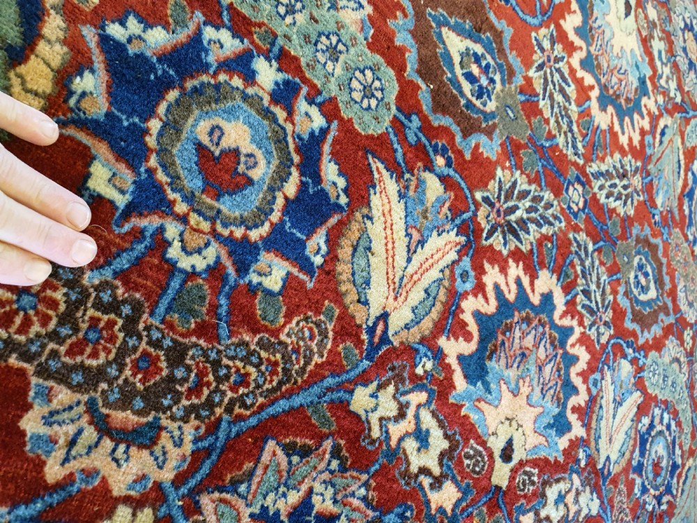 A large hand-knotted antique Tabriz carpet with an intricate floral motif across a red central field and a dark navy border. View III