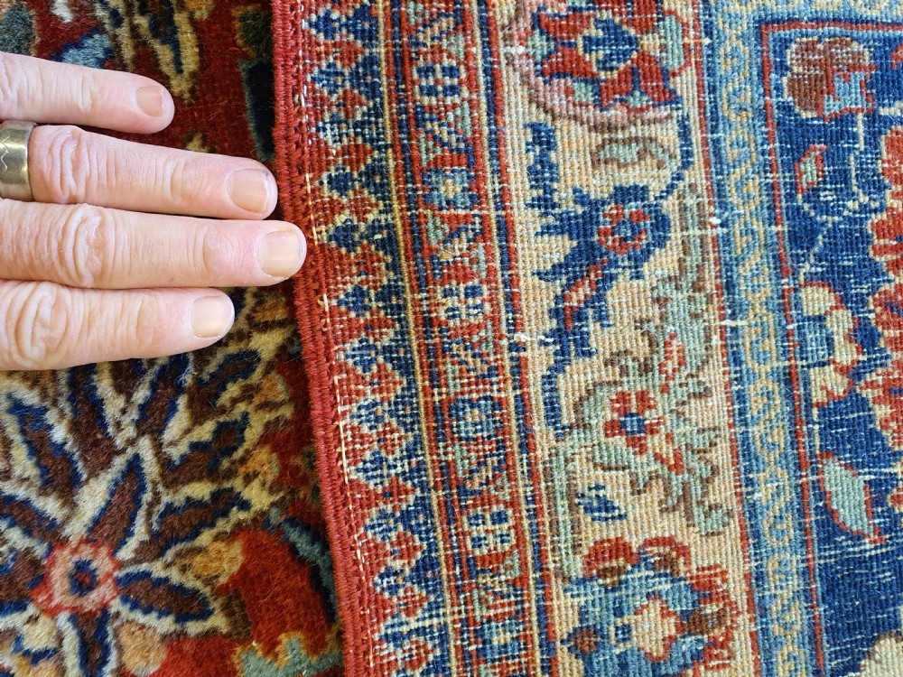 A large hand-knotted antique Tabriz carpet with an intricate floral motif across a red central field and a dark navy border. View IV