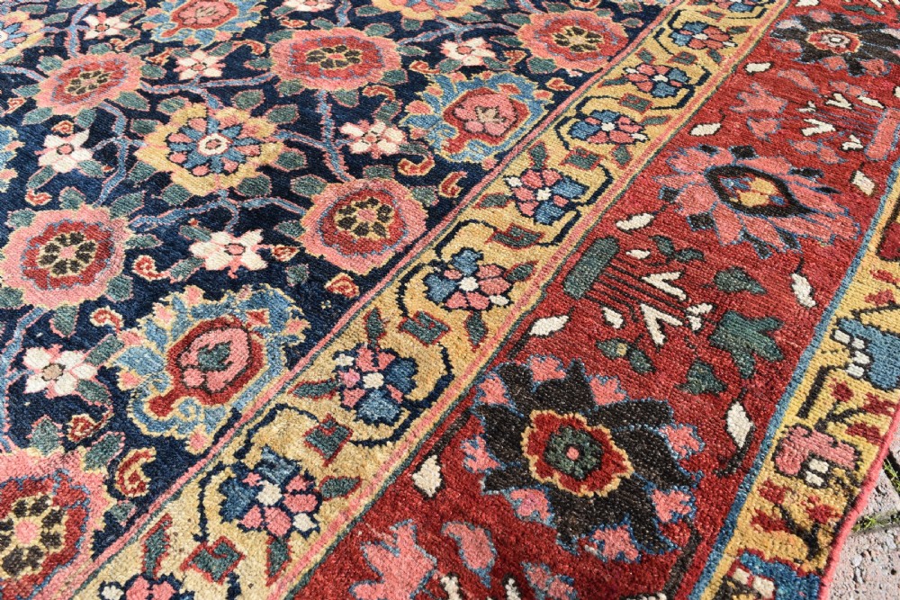 An elongated hand-knotted antique wool Kurdish Kelleh carpet featuring a repeating floral lattice pattern on a dark navy field surrounded by a patterned red border. View III