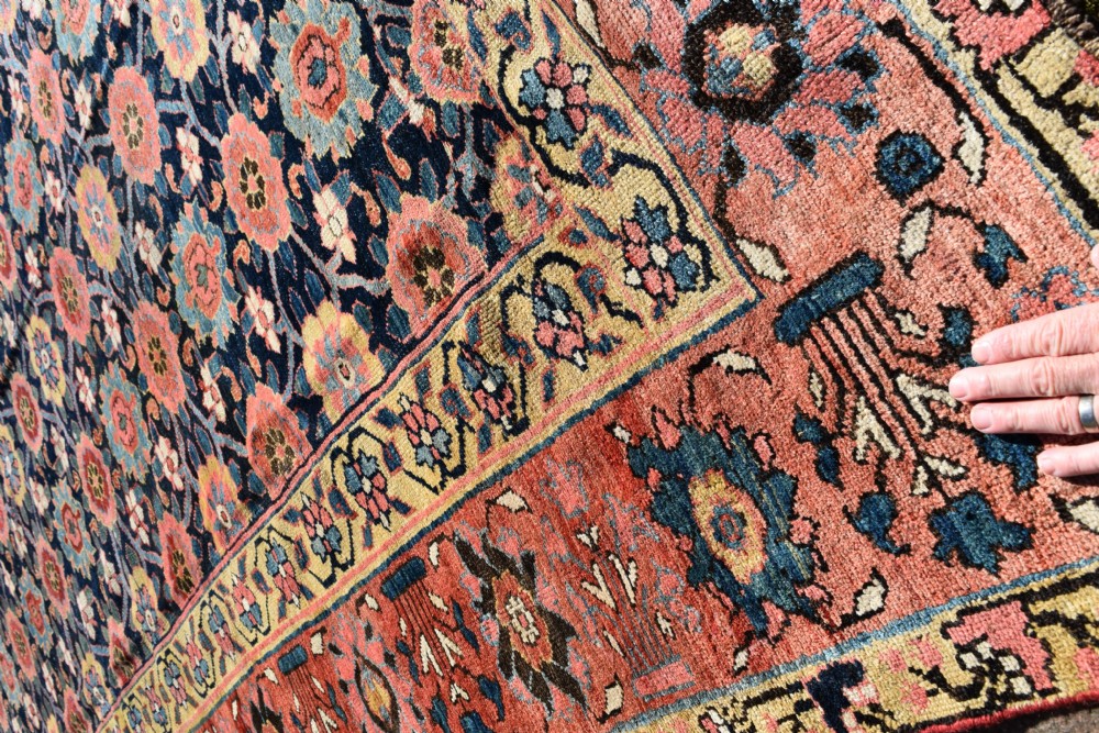 An elongated hand-knotted antique wool Kurdish Kelleh carpet featuring a repeating floral lattice pattern on a dark navy field surrounded by a patterned red border. View V