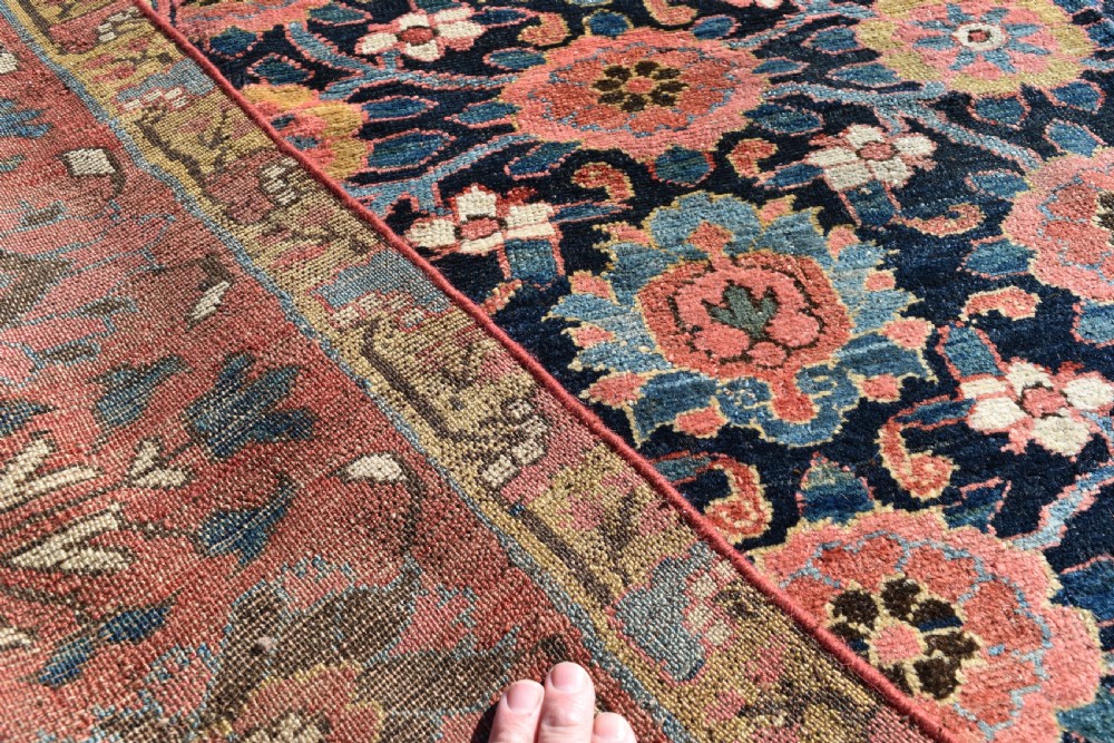 An elongated hand-knotted antique wool Kurdish Kelleh carpet featuring a repeating floral lattice pattern on a dark navy field surrounded by a patterned red border. View VI