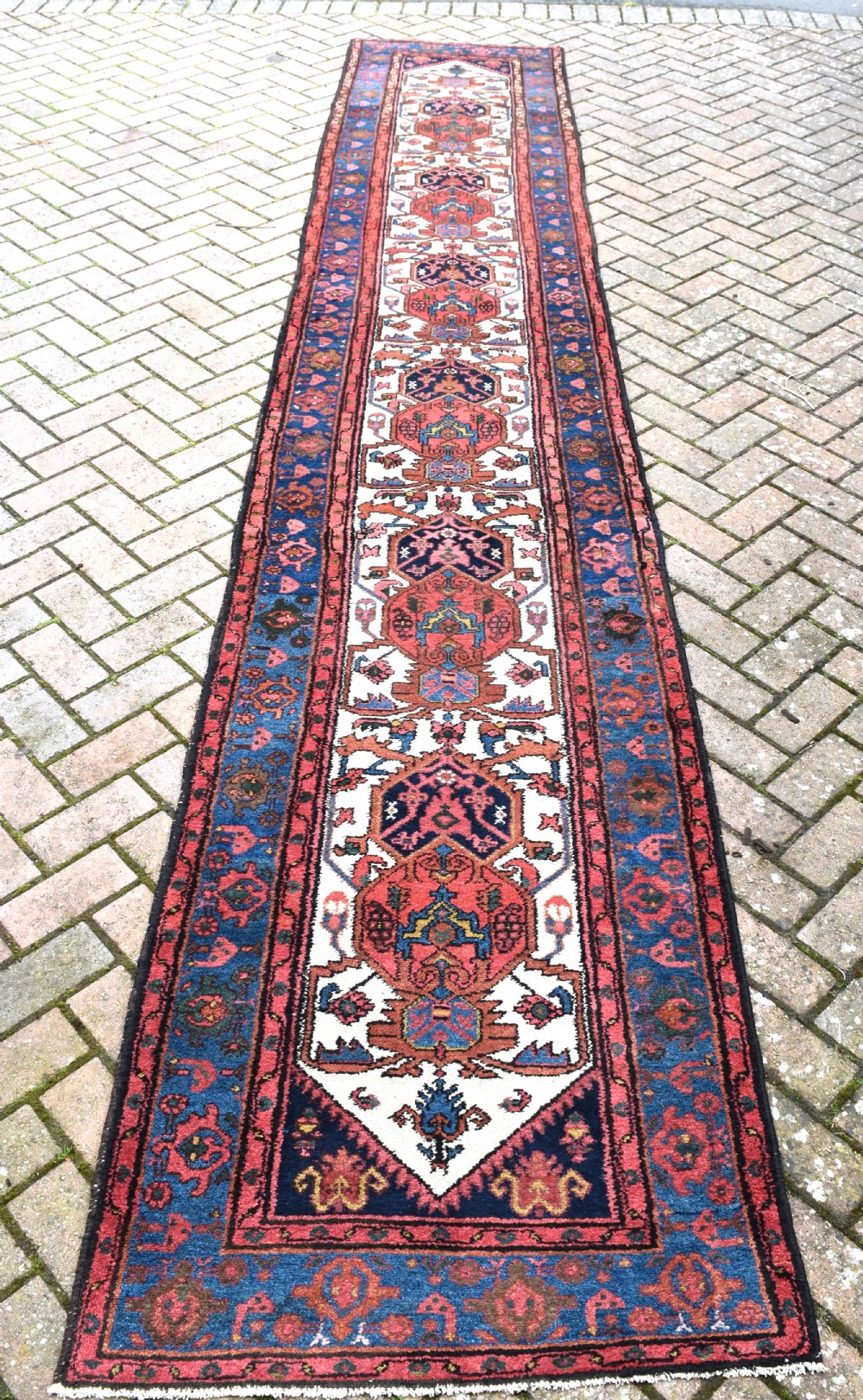 An extra long antique Persian Malayer runner rug featuring repeating geometric medallions on an ivory field with red and navy blue borders. View II