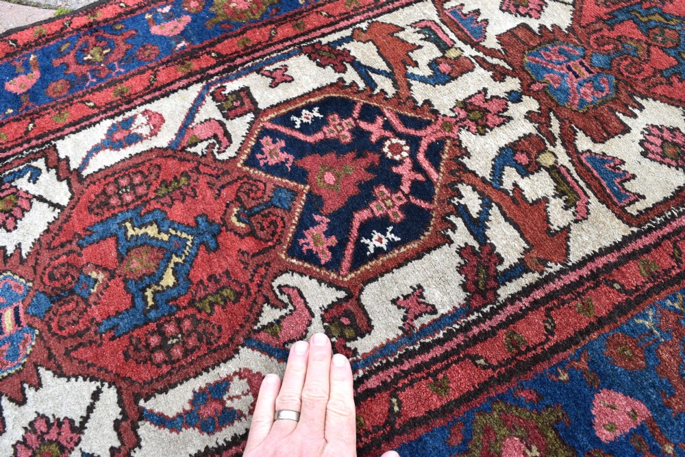 An extra long antique Persian Malayer runner rug featuring repeating geometric medallions on an ivory field with red and navy blue borders. View III