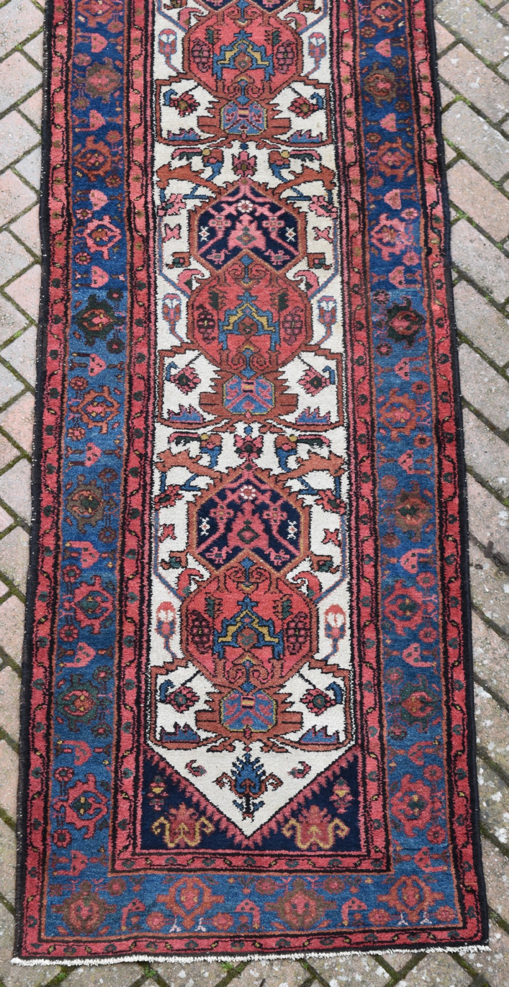 An extra long antique Persian Malayer runner rug featuring repeating geometric medallions on an ivory field with red and navy blue borders. View V