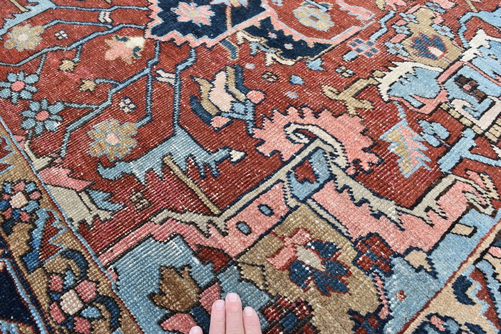 An antique hand-knotted Persian Heriz carpet featuring a large geometric central medallion in navy blue, light blue, and terracotta surrounded by ornate botanical borders. View IV