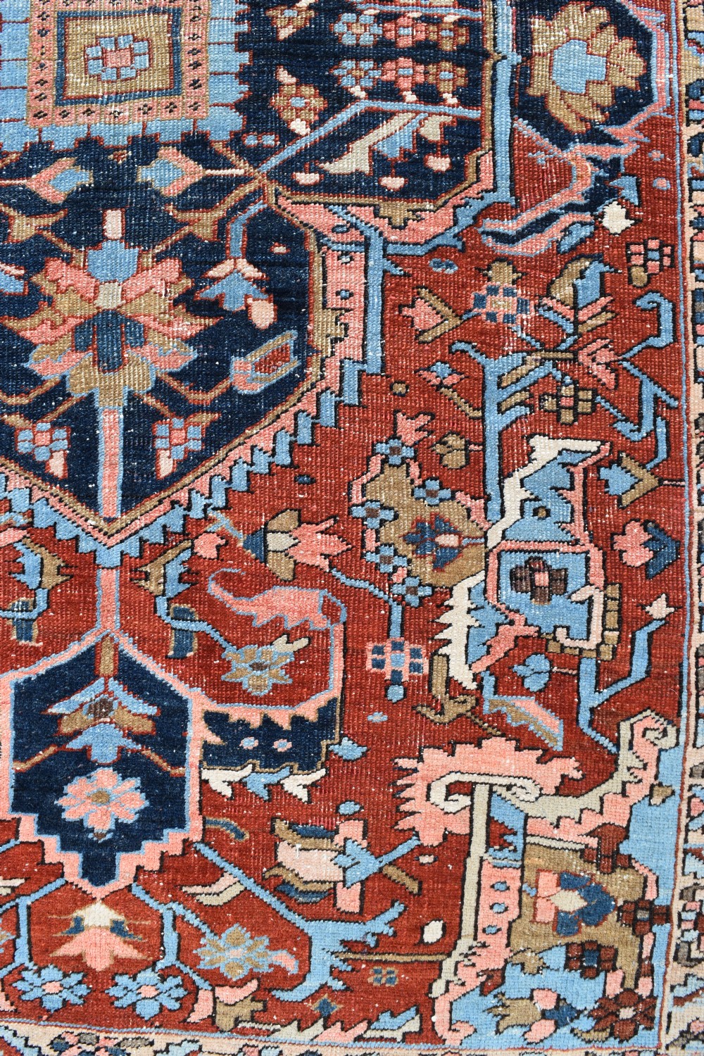 An antique hand-knotted Persian Heriz carpet featuring a large geometric central medallion in navy blue, light blue, and terracotta surrounded by ornate botanical borders. View VII