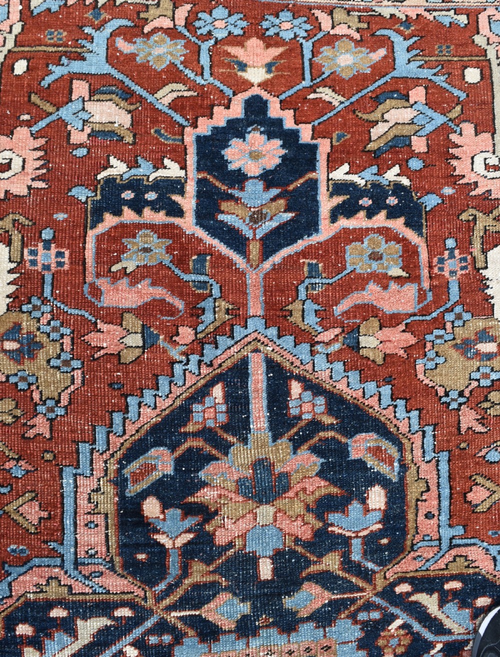An antique hand-knotted Persian Heriz carpet featuring a large geometric central medallion in navy blue, light blue, and terracotta surrounded by ornate botanical borders. View VIII