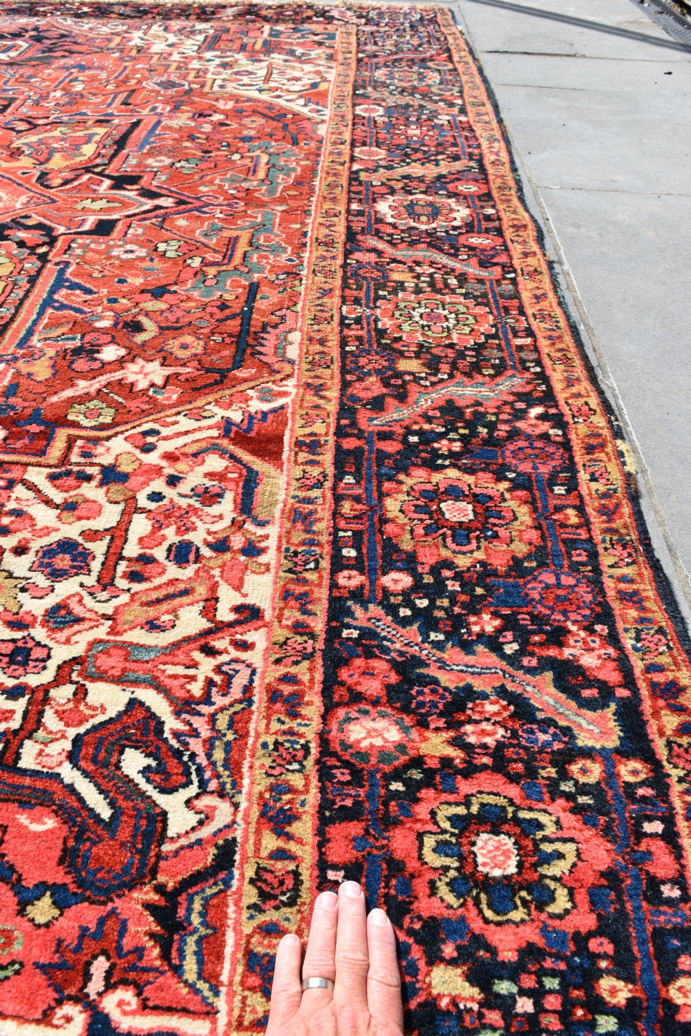An antique hand-knotted Heriz wool rug featuring a large geometric central medallion in navy and ivory surrounded by a terracotta red field and patterned borders. View IV