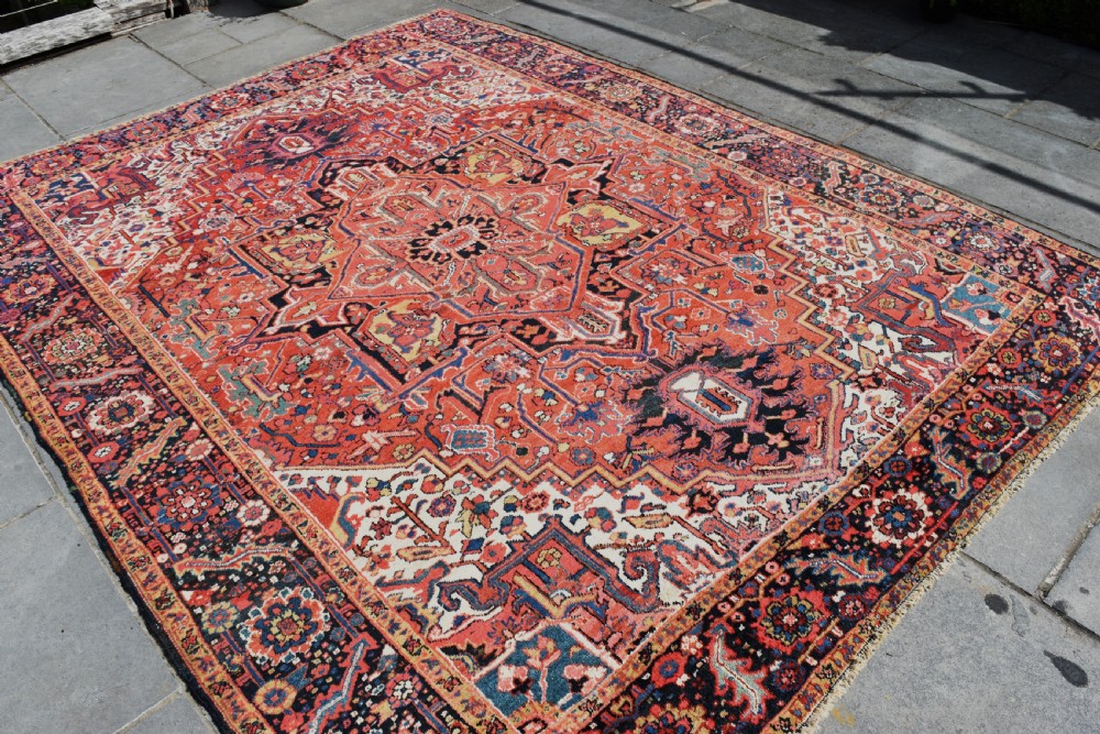 An antique hand-knotted Heriz wool rug featuring a large geometric central medallion in navy and ivory surrounded by a terracotta red field and patterned borders. View VI