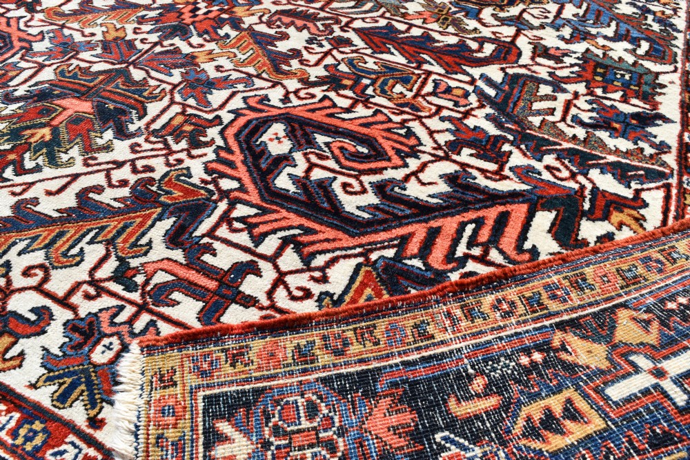 A large antique hand-knotted Heriz wool carpet featuring an allover cream field decorated with intricate geometric floral motifs and framed by a dark navy patterned border. View II