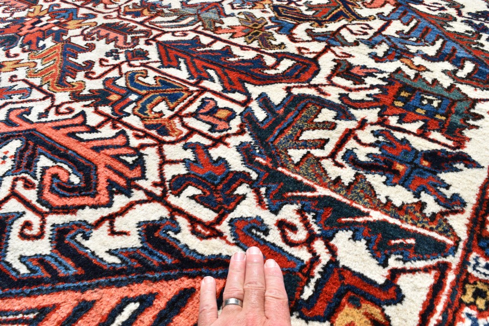 A large antique hand-knotted Heriz wool carpet featuring an allover cream field decorated with intricate geometric floral motifs and framed by a dark navy patterned border. View III