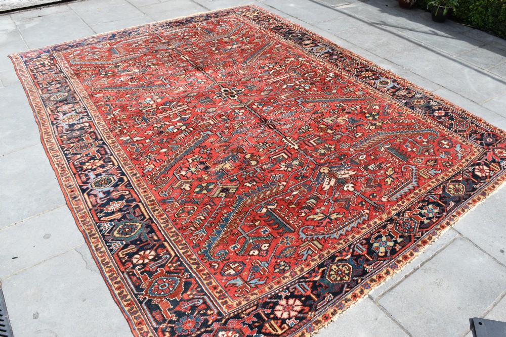 A large hand-knotted Persian Heriz carpet displaying a dense geometric all-over motif in terracotta red, sky blue, and navy blue. View III