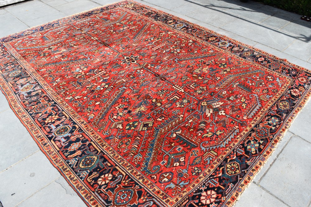 A large hand-knotted Persian Heriz carpet displaying a dense geometric all-over motif in terracotta red, sky blue, and navy blue. View IV