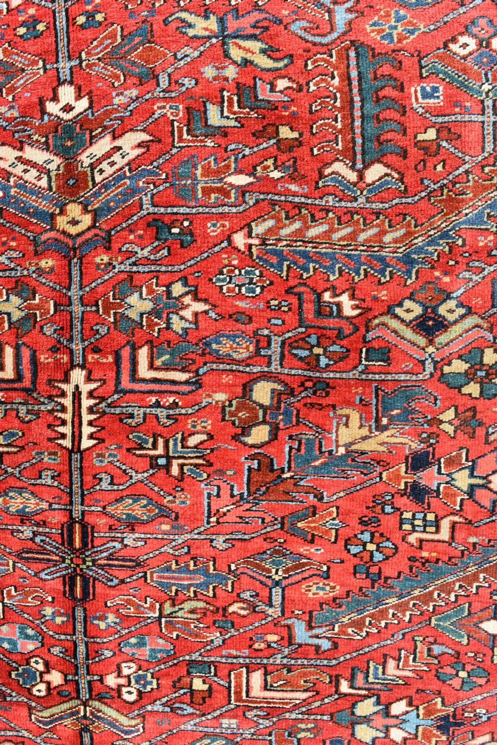 A large hand-knotted Persian Heriz carpet displaying a dense geometric all-over motif in terracotta red, sky blue, and navy blue. View VI