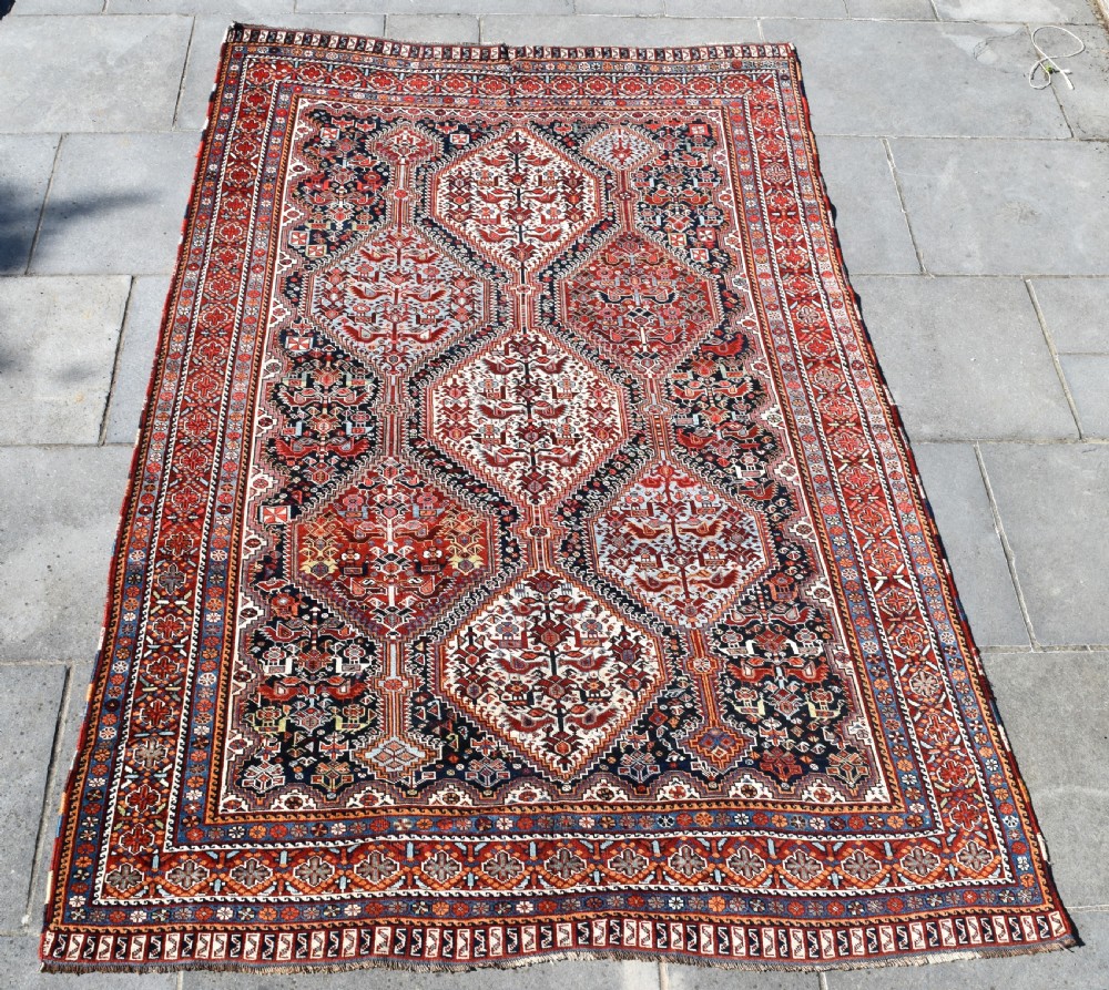 A large hand-knotted wool carpet featuring red, navy, and cream diamond medallions containing stylized bird motifs framed by intricate geometric borders. View II